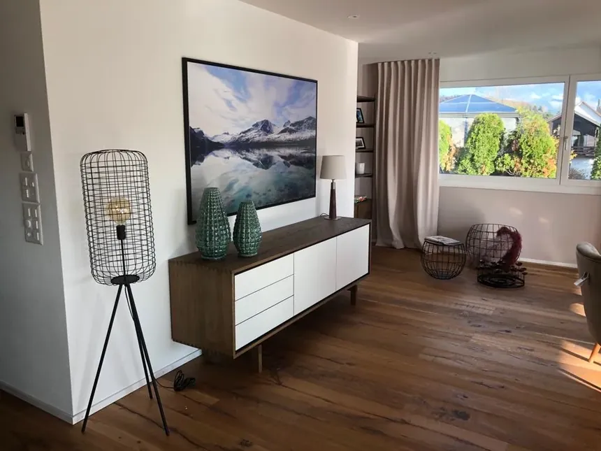 Wohnbereich mit Sideboard, Beleuchtung und Bergmotiv